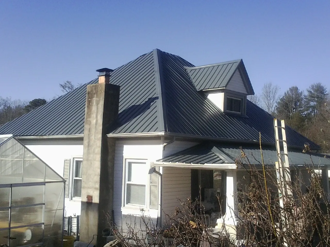Dark blue standing seam metal roof on a white farmhouse with dormer — Slate & Tile Roof Repair by Roofing Brothers in Glastonbury