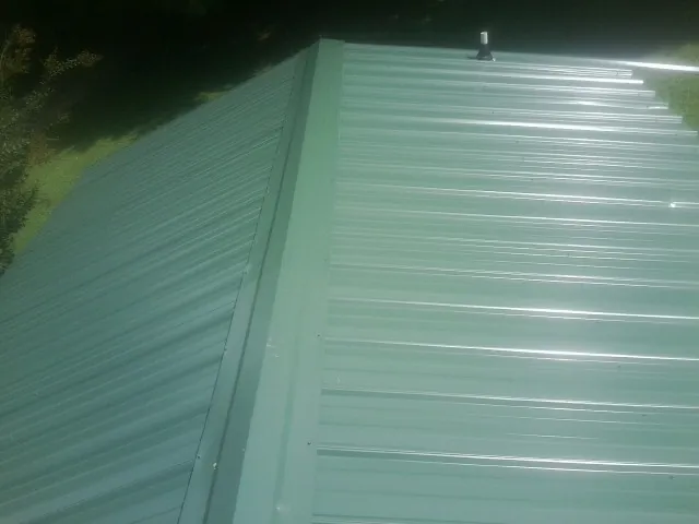 New green metal panels meeting at the ridge of a roof — Flat Roof Repair work by our crew in Glastonbury