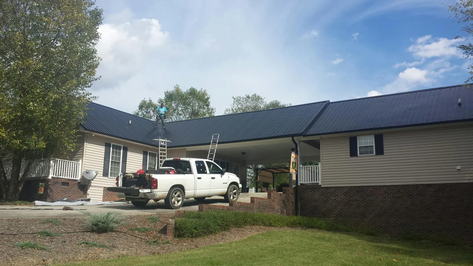 Black metal roof over a home and attached breezeway with ladders set in Glastonbury