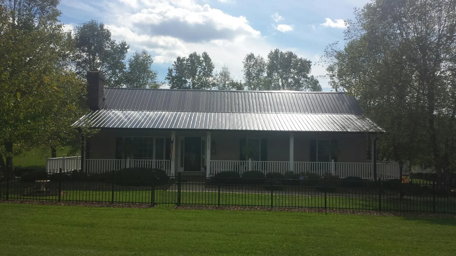 Gray metal roof on a brick ranch with a full width front porch — Gutter Guard Installation work by our crew in Glastonbury