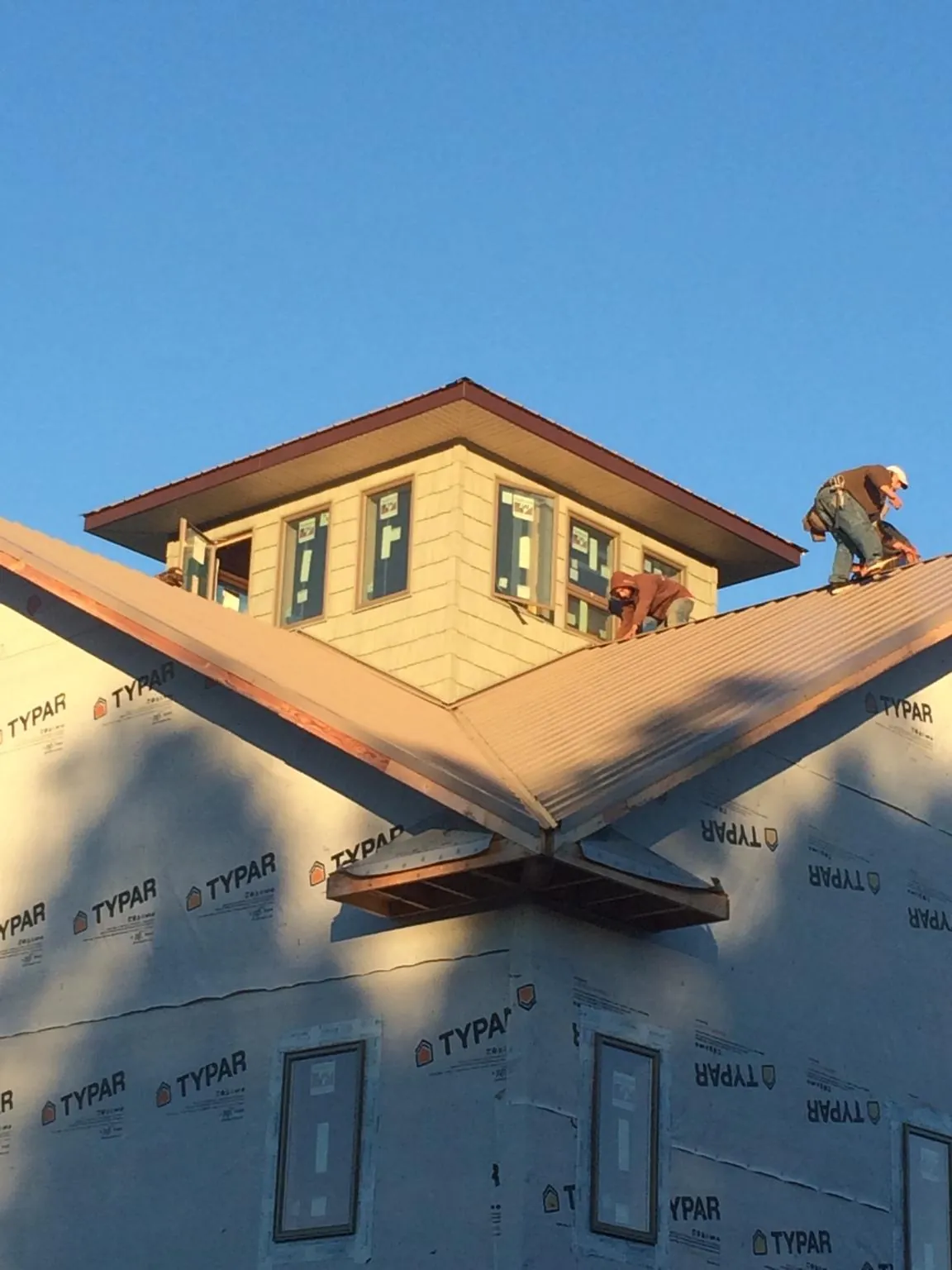 Roofers working around a rooftop cupola on a new metal roof at sunset — Roof Waterproofing in Glastonbury by Roofing Brothers